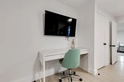 a white desk with a green chair and a television on a wall at Captivating 2-BR apartment for 5 people V3 in Miami