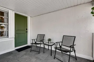 two chairs and a table on a porch with a green door at Captivating 2-BR apartment for 5 people V3 in Miami