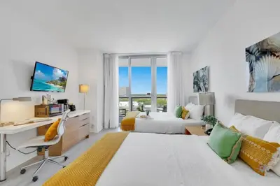 a white bedroom with a desk and a bed at To Steps from the Beach - Coastal Bliss, Pool- Gym in Hallandale Beach
