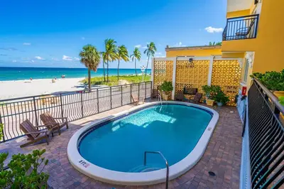 a swimming pool next to a building and the beach at Beach Front 1 Bedroom with Ocean View, Pool and Parking in Hollywood