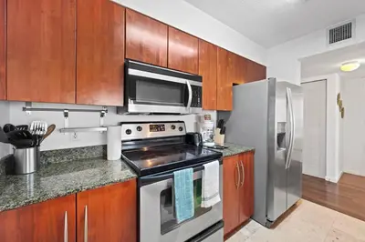 a kitchen with stainless steel appliances and wooden cabinets at Well Located Unit with parking - Heart Of Brickell in Miami