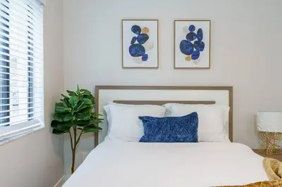 a bedroom with a white bed with blue pillows at New Miami & Calle Ocho Home with Arcade! in Miami