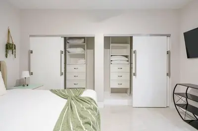 a bedroom with white walls and a bed and a mirror at New Miami & Calle Ocho Home with Arcade! in Miami