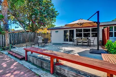 a home with a red bench and an umbrella at Citrus Isles Waterfront Home in Fort Lauderdale