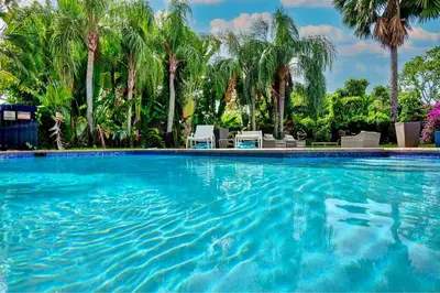 a swimming pool with blue water and palm trees at Breathtaking Pool Home and Backyard by Wilton Mnrs in Fort Lauderdale