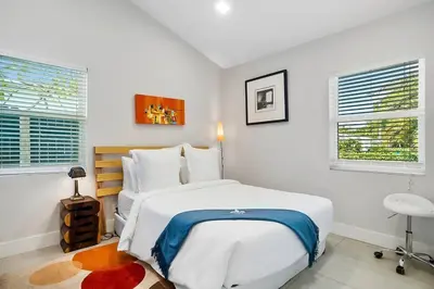 a white bedroom with a large bed and two windows at Breathtaking Pool Home and Backyard by Wilton Mnrs in Fort Lauderdale