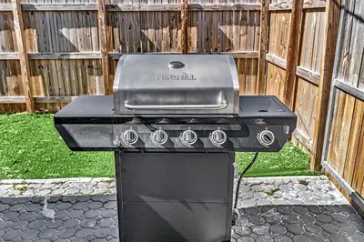a grill sitting in a yard next to a fence at 3 Bedroom Villa In F Lauderdale Casino & Beach in Fort Lauderdale