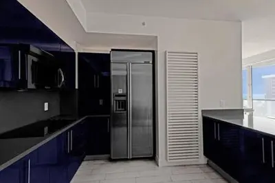 a kitchen with a stainless steel refrigerator and blue cabinets at WVR Vacation Residences 709 in Fort Lauderdale