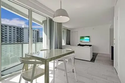 a dining room with a glass table and chairs in a living room at WVR Vacation Residences 709 in Fort Lauderdale