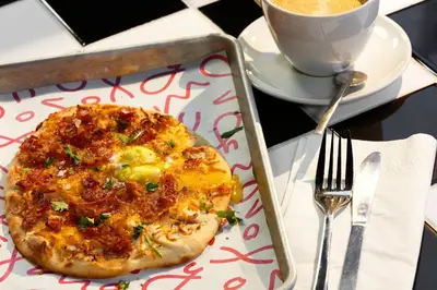 a pizza in a tray with a fork and a cup of coffee at Moxy Miami Wynwood in Miami