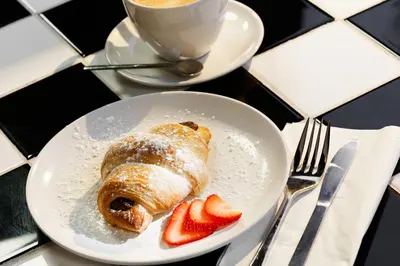 a pastry on a plate with strawberries and a cup of coffee at Moxy Miami Wynwood in Miami