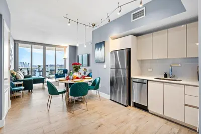 a kitchen and living room with a table and chairs at Ocean Views - Pool & Gym - Pet Friendly - Close to Beach in Hallandale Beach
