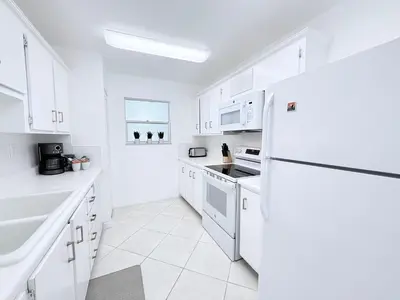 a white kitchen with white cabinets and a refrigerator at Le Cartier Sunny Isles Ocean Paradise in Sunny Isles Beach