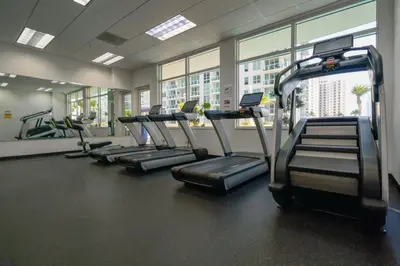 a gym with rows of treadmills in front of windows at Cloud 9 - Amenities 24 7 Security & Location in Miami