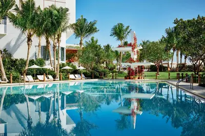 a swimming pool at a resort with palm trees at The Miami Beach EDITION in Miami Beach