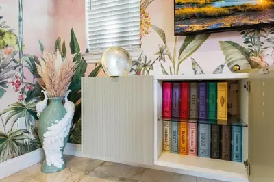a book shelf filled with books next to a vase at The Betty A Glam Getaway in Fort Lauderdale in Fort Lauderdale