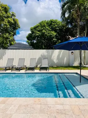 a swimming pool with a blue umbrella and chairs at Miami Getaway Heated Pool Villa with Mini Golf & BBQ in Miami