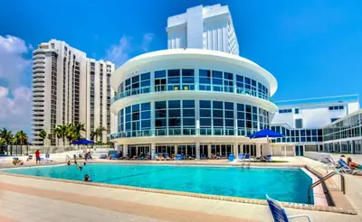 a large building with a swimming pool in front of it at Castle Ph11 Penthouse with Balcony, Free Parking, Pool, Tennis, Beach Access in Miami Beach