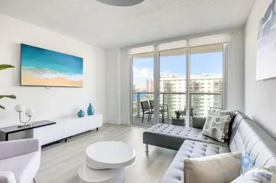 a living room with a couch and a large window at Beachside Bliss: 1BR Retreat Amenities in Sunny Isles Beach