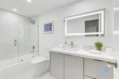 a white bathroom with a toilet and a sink at Beachside Bliss: 1BR Retreat Amenities in Sunny Isles Beach