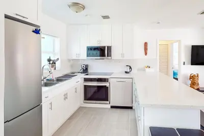 a white kitchen with a sink and a refrigerator at Palm Shadow Sanctuary in Fort Lauderdale