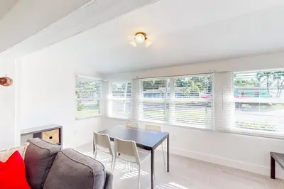 a living room with a table and chairs and windows at Palm Shadow Sanctuary in Fort Lauderdale