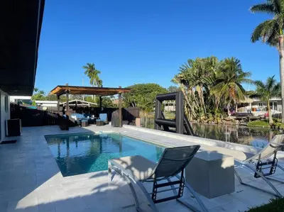 a swimming pool with two chairs and a table at Modern pool home on the lake near Hardrock FLL airport in Davie