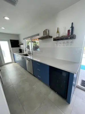 a kitchen with a white counter and blue cabinets at Modern pool home on the lake near Hardrock FLL airport in Davie