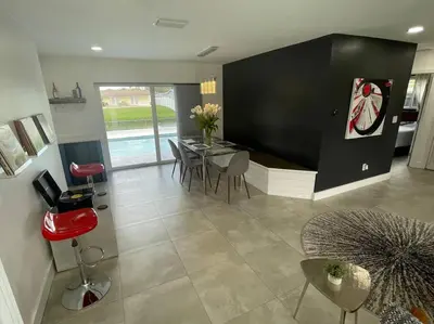 a living room with a dining table and chairs at Modern pool home on the lake near Hardrock FLL airport in Davie