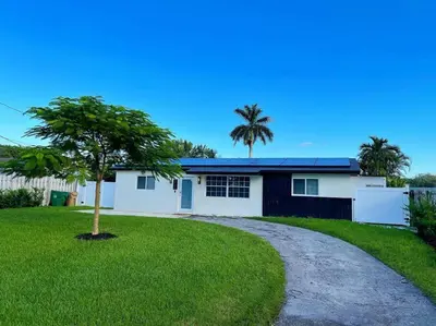 a house with a palm tree and a driveway at Modern pool home on the lake near Hardrock FLL airport in Davie