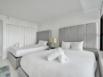two beds in a hotel room with white at Beautiful Beach Condo Beach Service 1020 in Miami Beach
