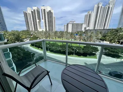 a balcony with two chairs and palm trees and buildings at Ocean Reserve Condo by FlatsAway in Miami Beach