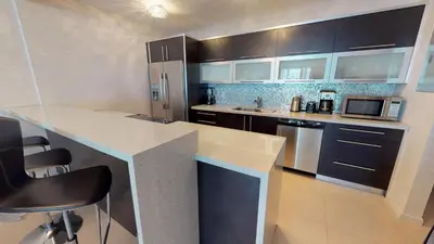 a kitchen with stainless steel appliances and black cabinets at Ocean Reserve Condo by FlatsAway in Miami Beach