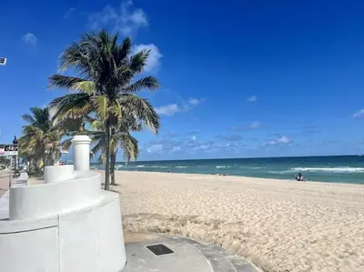 a sandy beach with palm trees and the ocean at Ocean Breeze Free Parking Apt 3 in Fort Lauderdale