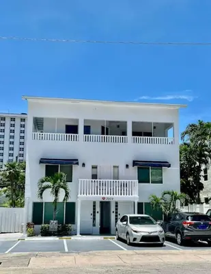 a white house with two cars parked in a parking lot at Ocean Breeze Free Parking Apt 3 in Fort Lauderdale