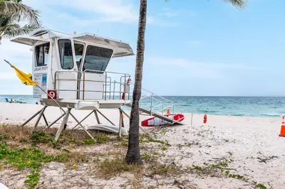 a lifeguard boat on the beach next to a palm tree at Ocean Breeze Paradise Apt 5A in Fort Lauderdale