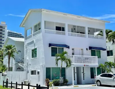 a white house with a car parked in front of it at Ocean Breeze Paradise Apt 5A in Fort Lauderdale