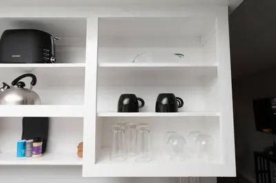 a white book shelf with glass utensils at Short Walk to Wilton Drive Apt1 in Fort Lauderdale