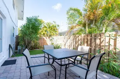 a table and chairs on a patio with palm trees at Short Walk to Wilton Drive Apt3 in Fort Lauderdale