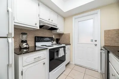 a kitchen with white cabinets and a stove top oven at Short Walk to Wilton Drive Apt3 in Fort Lauderdale