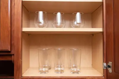 four empty glasses sitting on a shelf in a cabinet at Short Walk to Wilton Drive Apt4 in Fort Lauderdale