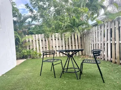 three chairs and a table in a yard with a fence at Short Walk to Wilton Drive Apt6 in Fort Lauderdale