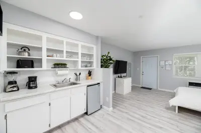 a white kitchen with a sink and a living room at Just Off Wilton Drive Apt 2 in Fort Lauderdale