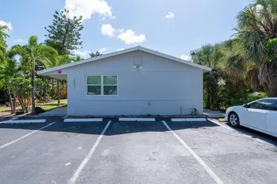 a white house in a parking lot with a car at Just Off Wilton Drive Apt 2 in Fort Lauderdale
