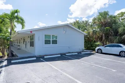 a white house with a car parked in a parking lot at Just Off Wilton Drive Apt 5 in Fort Lauderdale