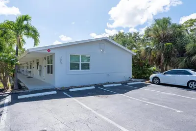 a white house with a car parked in a parking lot at Just Off Wilton Drive Apt 5 in Fort Lauderdale