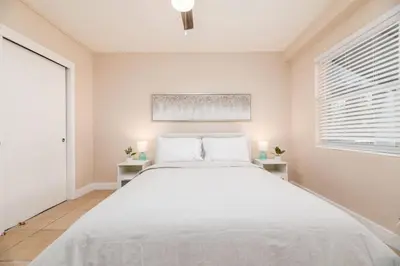 a white bedroom with a large bed and two windows at The Residences at Lake Ridge Apt 2 in Fort Lauderdale