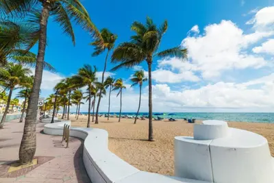 a sandy beach with palm trees and the ocean at The Residences at Lake Ridge Apt 2 in Fort Lauderdale