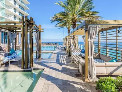 a resort pool with lounge chairs and palm trees at LYFE on the Beach 25th floor 1 bed unit with Oceanview in Hollywood