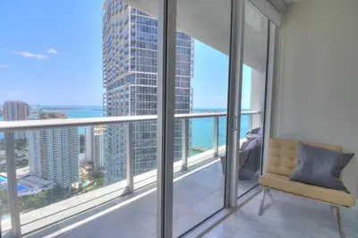 a balcony with a chair and a view of the ocean at Lux 2BR - Water View - Pool - Spa - FREE Parking in Miami